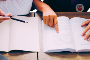Seorang mahasiswa sedang belajar akuntansi dengan tutor privat, menggunakan buku catatan untuk memahami konsep akuntansi lebih baik